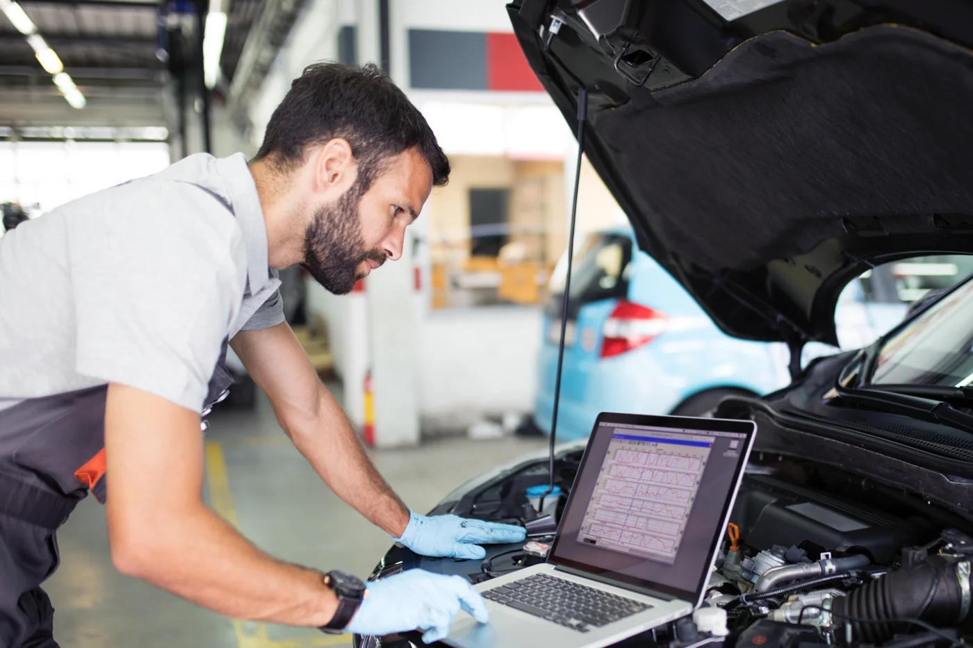 Technicien réalisant un diagnostic électronique avec un ordinateur en atelier